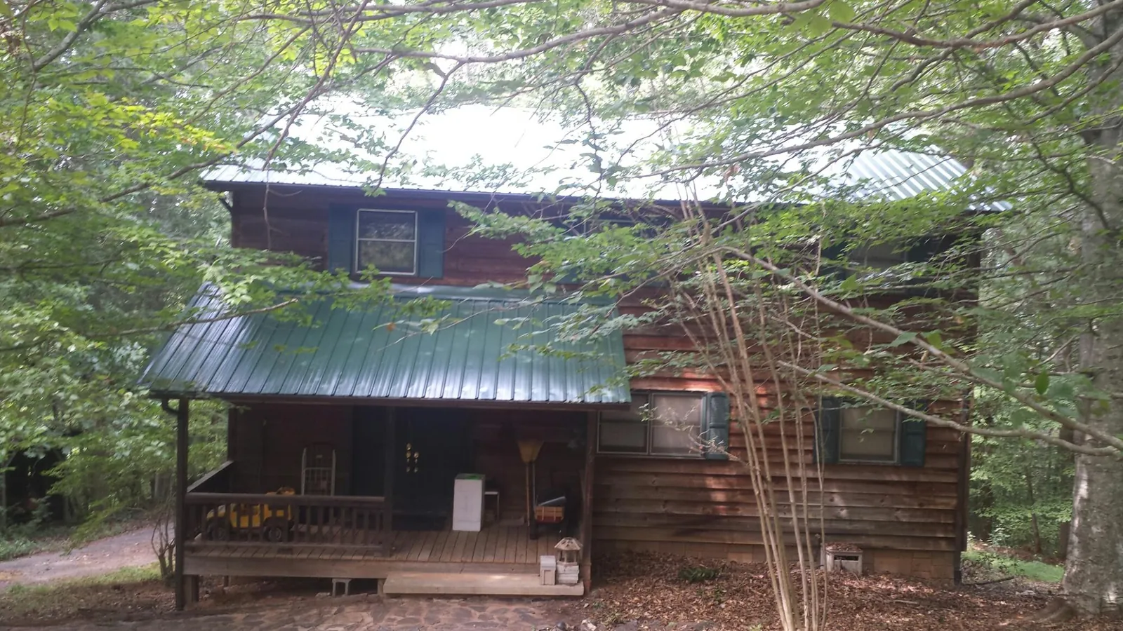 Green metal roof and covered porch on a log cabin in Marble Falls