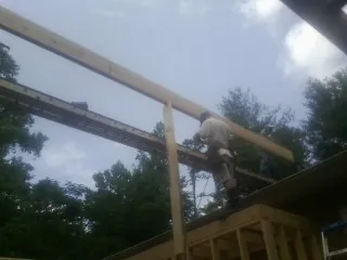 Carpenter setting a ridge beam over a new addition frame — Ice Dam Removal by Roofing Brothers in Marble Falls