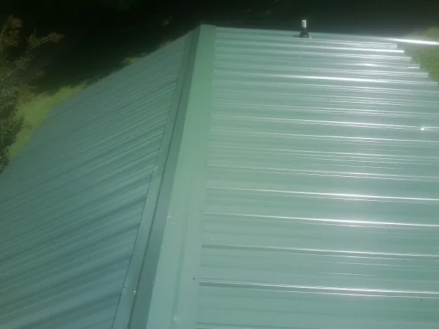 New green metal panels meeting at the ridge of a roof — Flat Roof Repair work by our crew in Marble Falls