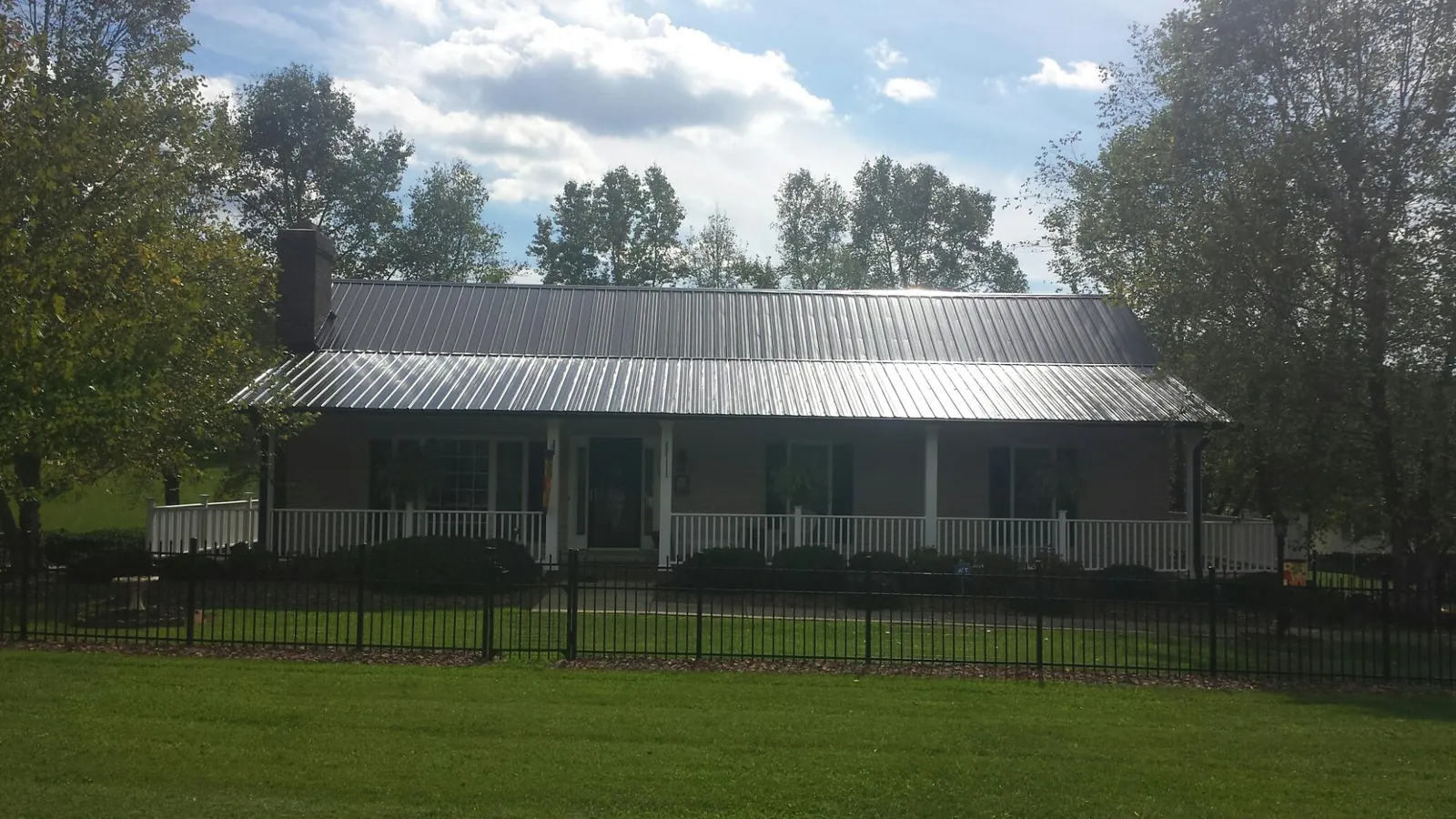 Gray metal roof on a brick ranch with a full width front porch — Gutter Guard Installation work by our crew in Marble Falls