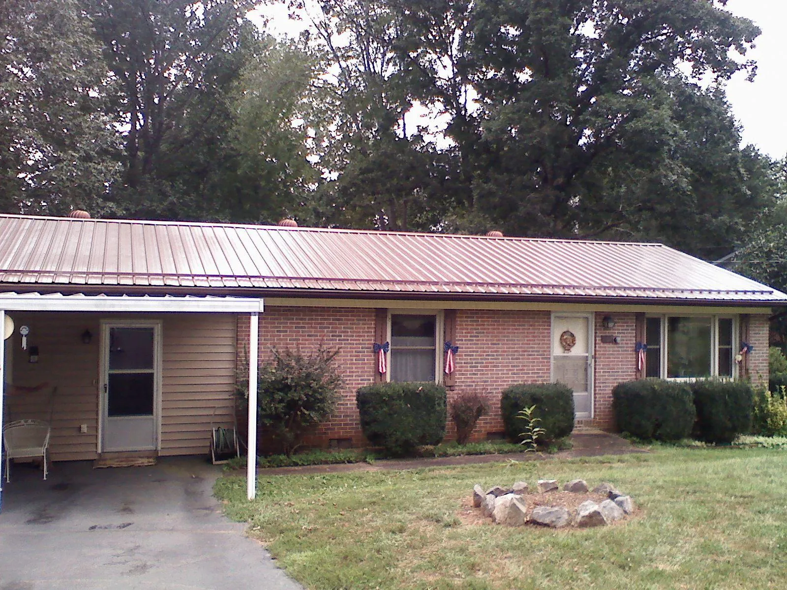Bronze metal roof and carport on a brick ranch home — Roof Repair work by our crew in Marble Falls