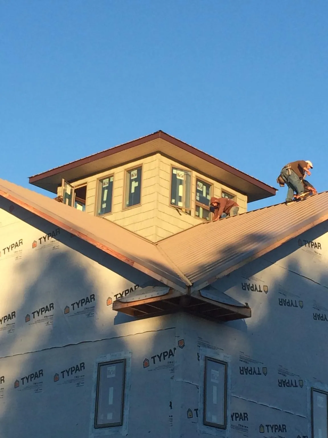 Roofers working around a rooftop cupola on a new metal roof at sunset — Roof Waterproofing in Marble Falls by Roofing Brothers